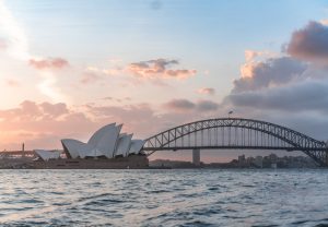 Stylish modern building and arch bridge crossing harbor against cloudy sundown sky, representing whistleblower protections in australia