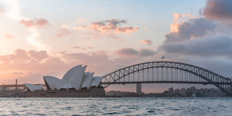 Australia Joint Committee Recommends More Helpful Whistleblower Protections 8 Stylish modern building and arch bridge crossing harbor against cloudy sundown sky, representing whistleblower protections in australia