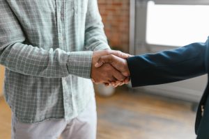 A Person in Green Plaid Long Sleeve Shirt Shaking Hands with Person in Black Blazer, representing SEC Whistleblowers or FCPA Enforcement Action