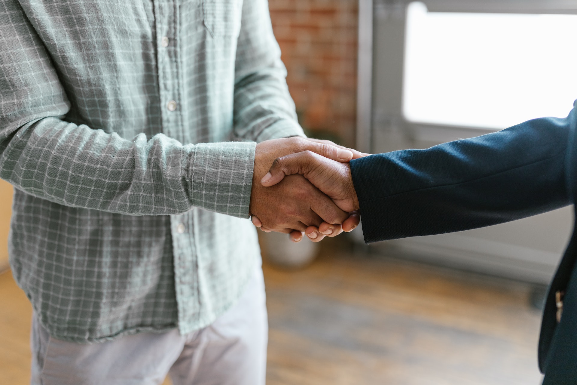 A Person in Green Plaid Long Sleeve Shirt Shaking Hands with Person in Black Blazer, representing SEC Whistleblowers or FCPA Enforcement Action