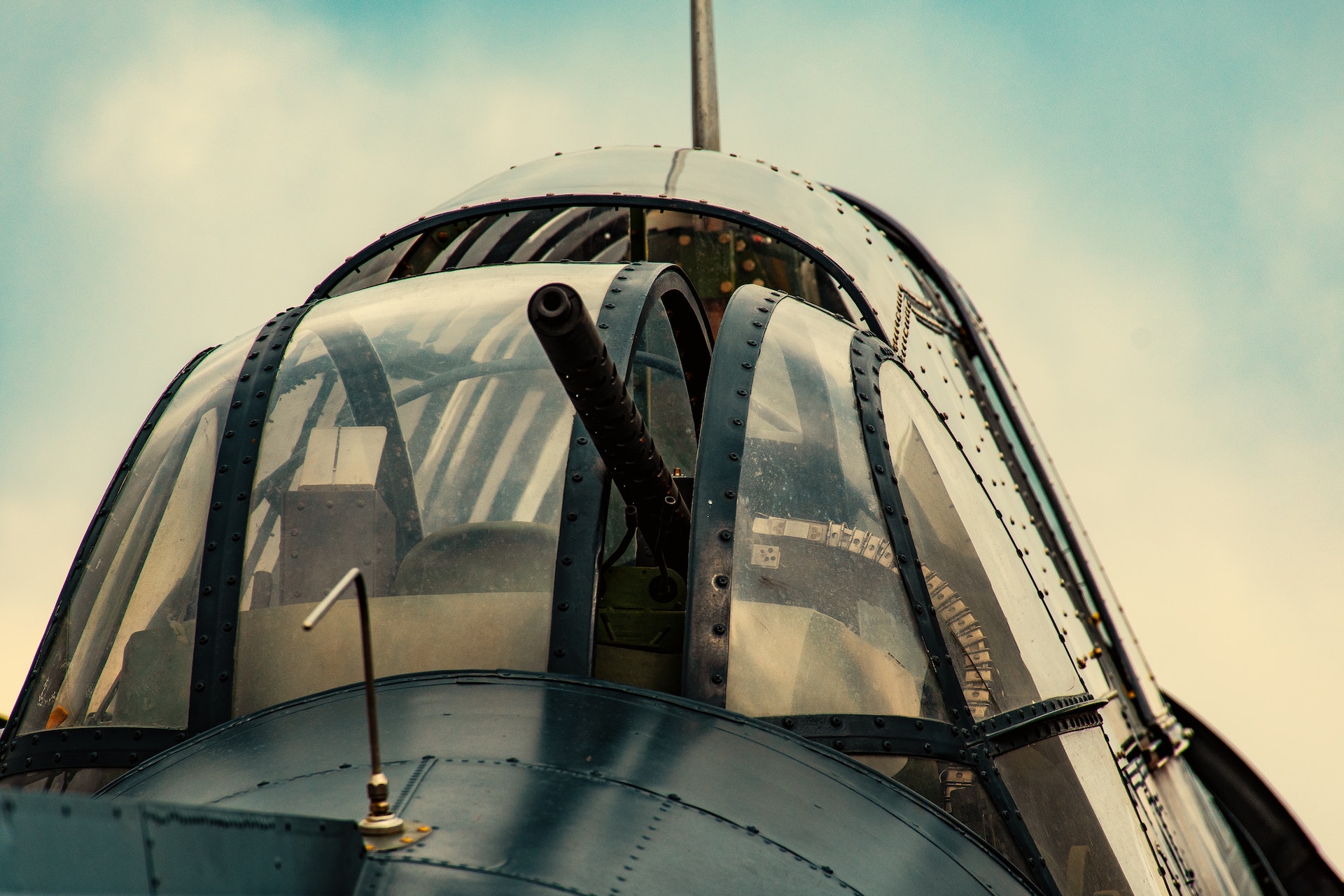 Cockpit view of a military aircraft with a prominent gun, illustrating the contrast between office supply fraud and defense contracting issues discussed in the article.