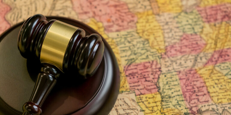 State-Level Justice: Why State False Claims Acts are the New Frontier for Whistleblowers 10 Judge's wooden gavel and USA map. concept of the judicial system in many States, attorney's fees in different States, justice in the American