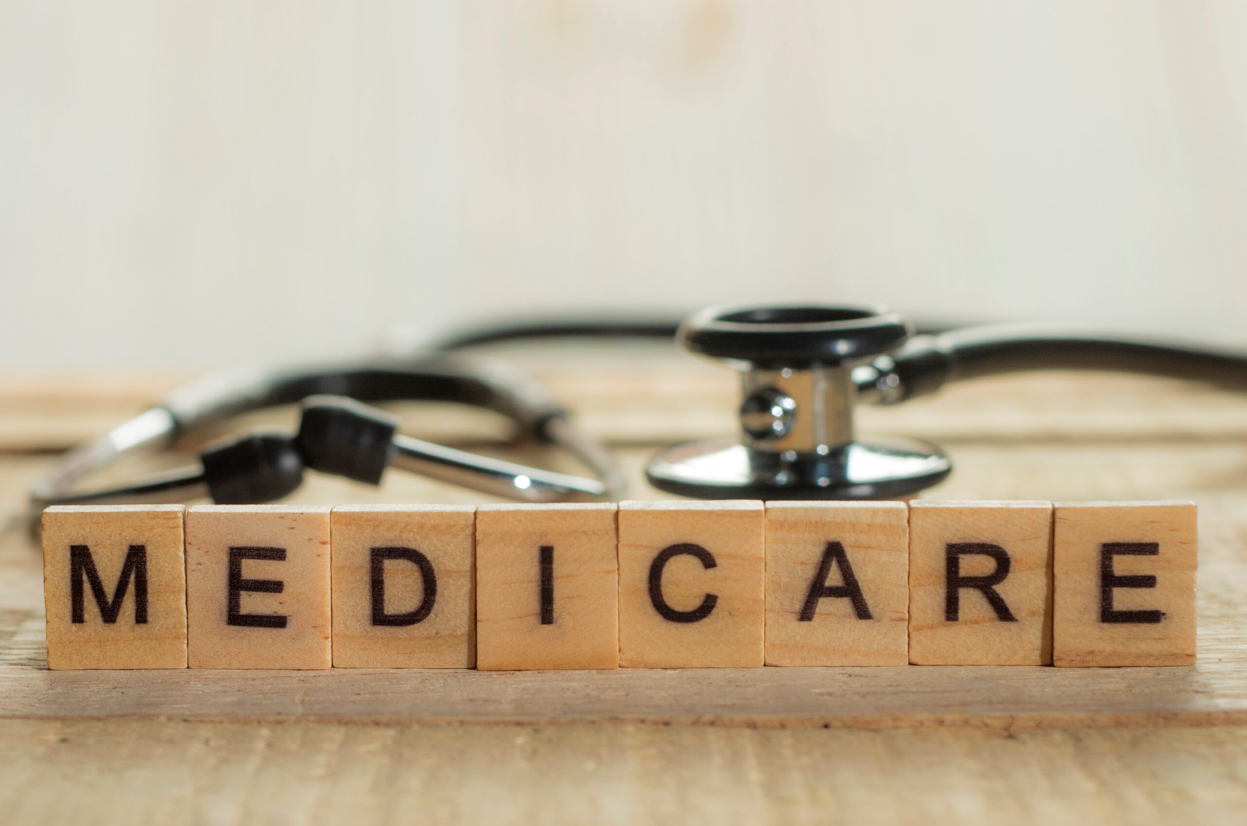 $27 Million Settlement for Violations of the False Claims Act in Healthcare 3 Wooden blocks spelling "MEDICARE" with a stethoscope in the background, symbolizing healthcare and Medicare fraud issues discussed in relation to false claims for unnecessary cancer genomic tests.